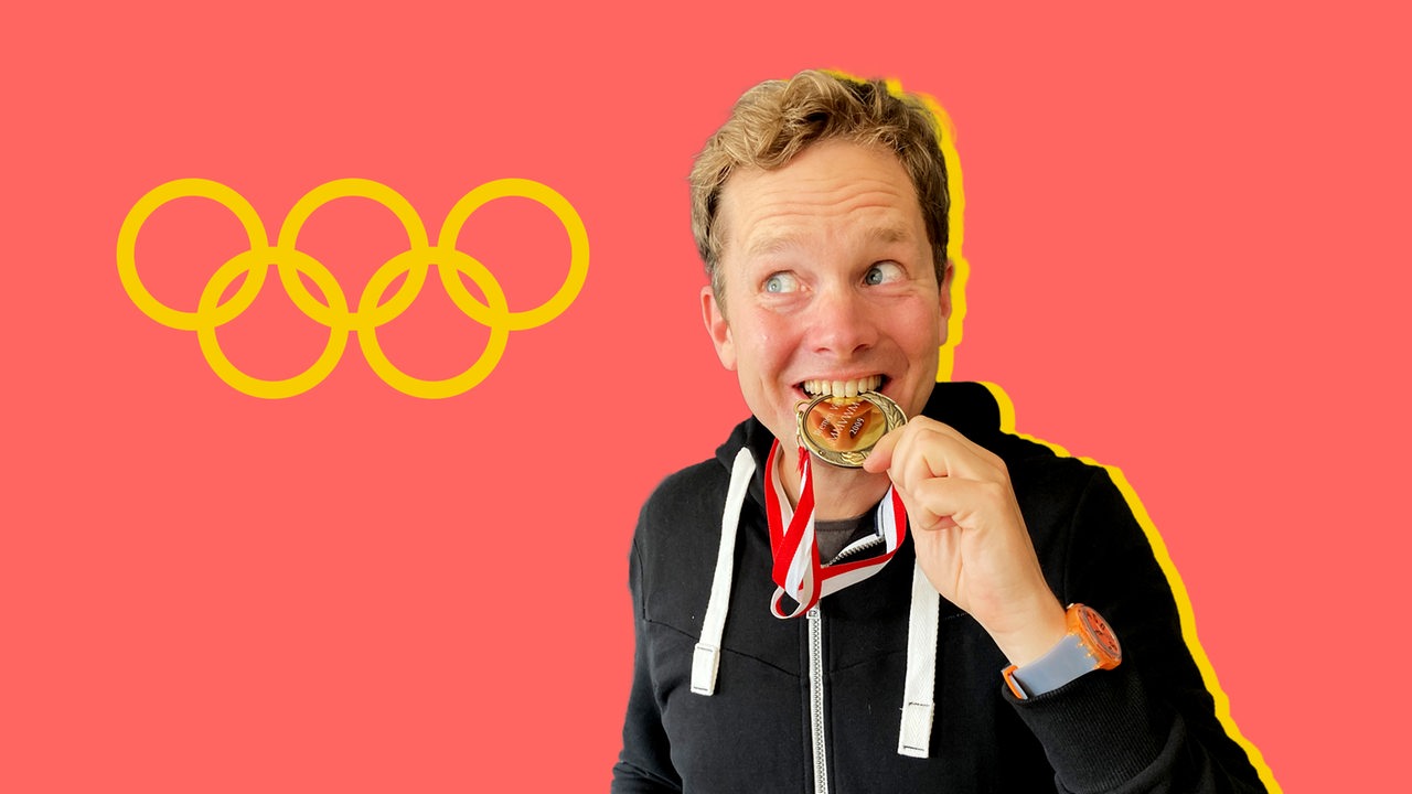 Ein Mann mit Gold-Medaille vor einem roten Hintergrund mit dem Olympia-Logo aus fünf Kreisen.