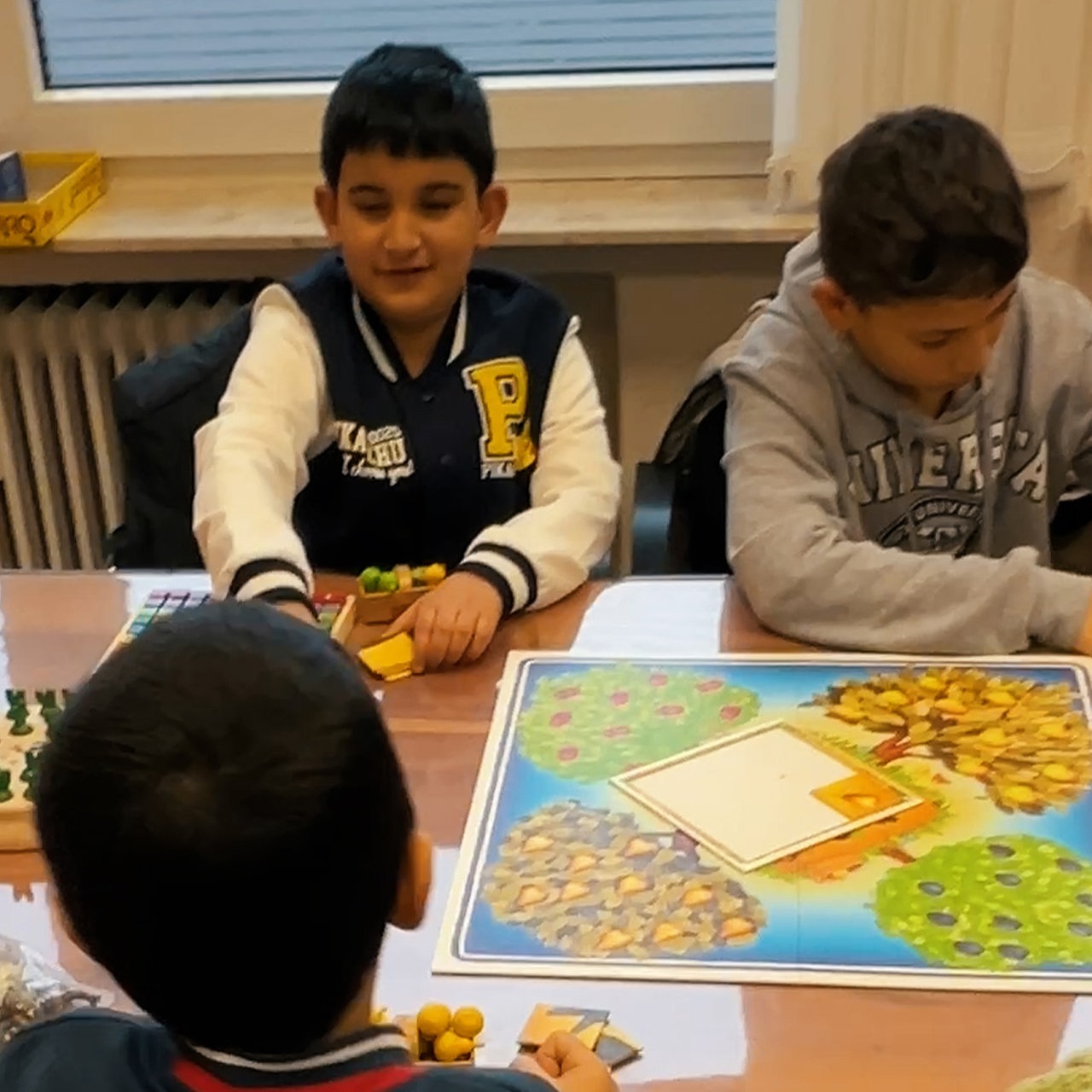 Kinder spielen an einem Tisch Gesellschaftsspiele